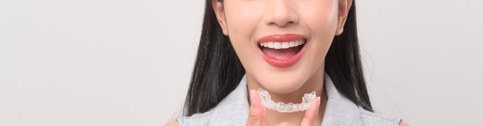 smiling woman holding clear aligner